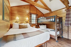 A cabin-style room with a bunk bed, two bedside lamps, and a window with curtains. - Riverfront Wilderness Cabin (Cullowhee)