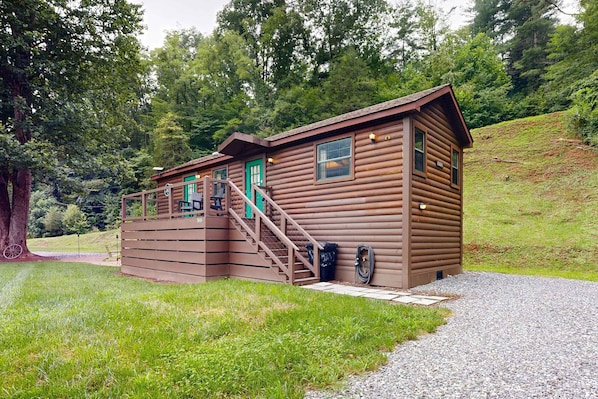 A wooden cabin with a porch, a door, and a window.