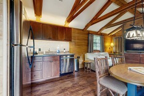 A kitchen with wooden cabinets, a stainless steel refrigerator, and a dining area with a round table and chairs.