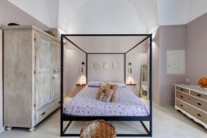 A four-poster bed with a floral bedspread, a wooden wardrobe, and a dresser with drawers. - Apartment 'Relais Filomarino Vacanze' with Private Pool, Wi-Fi and Air Conditioning (Corsano)
