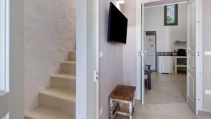 En trappa leder upp till ett köksområde med en platt-TV som är monterad på väggen.