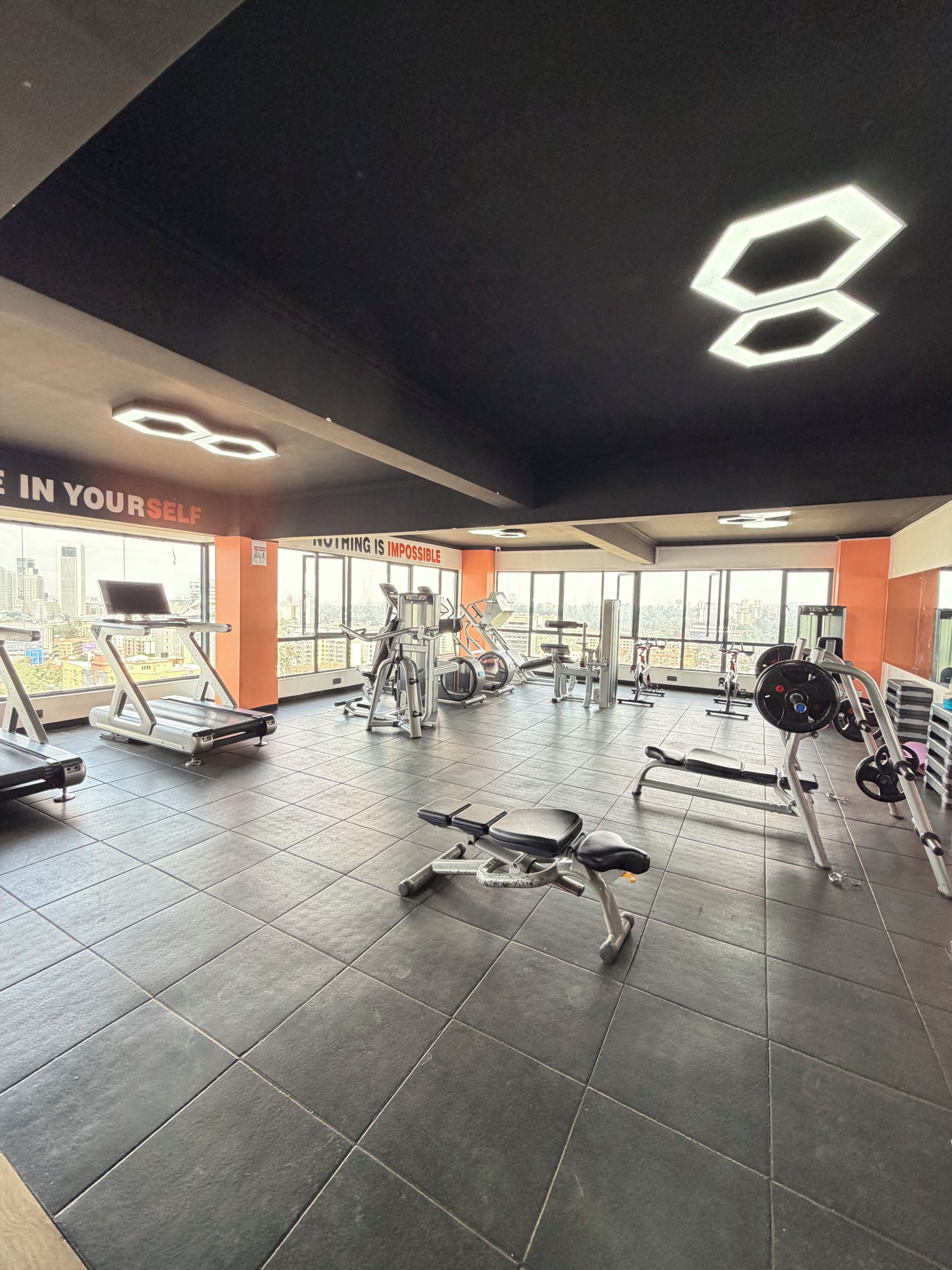A gym with various exercise equipment, a treadmill, and motivational wall quotes.