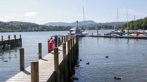 A wooden dock extending into calm water with boats docked at the pier. - High Perch (Windermere)