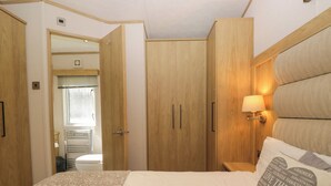 A bedroom with a bed, wooden wardrobe, and a nightstand with a lamp. - High Perch (Windermere)