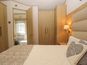 Un dormitorio con cama, armario de madera y mesita de noche con lámpara.
