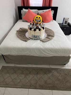 Ein Bett mit Geburtstagstorte, Kissen und einem Nachttisch mit Telefon.