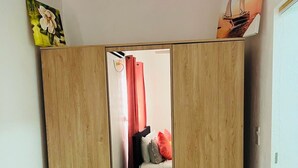 Quarto com armário de madeira, cama com almofadas e espelho.