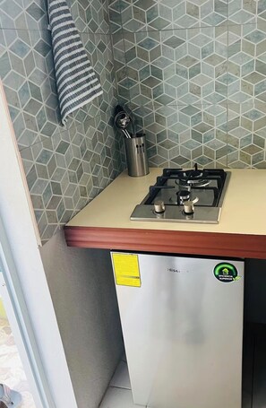 A compact kitchen with a gas stove, a stainless steel utensil holder, and a tiled backsplash. - Vibra Lux Island Escape Cozy 1BR Near Beaches & Philipsburg (Philipsburg)