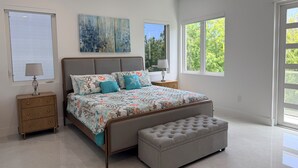 Un dormitorio moderno con una cama grande, un banco y dos mesitas de noche.