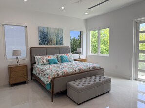 A modern bedroom with a large bed, a bench, and two nightstands. - #3 2-bedroom condo in tranquil Savannah with cool AC breeze (Savannah)