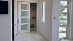 Un pasillo con un armario, una puerta que da al exterior y una ventana con vista a follaje.