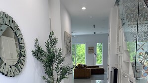 Un interior moderno con un aparador verde azulado, un espejo grande y un armario de vidrio con azulejos estampados.