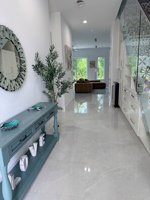 A modern interior with a teal console table, a large mirror, and a glass-fronted cabinet with patterned tiles. - #3 2-bedroom condo in tranquil Savannah with cool AC breeze (Savannah)