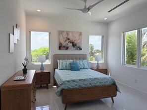 A bedroom with a bed, two bedside tables, a ceiling fan, and large windows. - #4 Delightful 2-bedroom condo with AC in charming Savannah (Savannah)