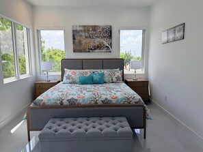 A bedroom with a bed, two bedside tables, a bench, and artwork on the walls. - #4 Delightful 2-bedroom condo with AC in charming Savannah (Savannah)