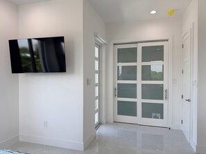 A modern interior with a flat-screen TV mounted on the wall, a sliding glass door leading to an outdoor area, and a clean, tiled floor. - #4 Delightful 2-bedroom condo with AC in charming Savannah (Savannah)