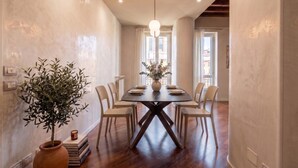 A dining area with a dark wooden table, six chairs, a vase with flowers, and a hanging light fixture. - ApartmentsArena - Capitolium Verona 5 (Verona)