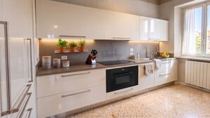 A modern kitchen with white cabinetry, a black oven, and a countertop with potted plants and kitchen essentials. - ApartmentsArena - Capitolium Verona 5 (Verona)