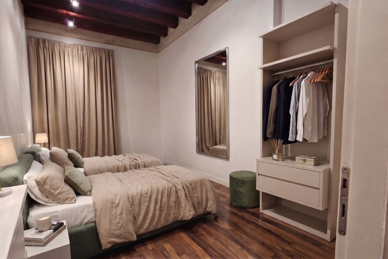 A bedroom with a bed, bedside table, lamp, wardrobe, and a mirror.