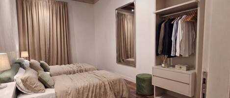 A bedroom with a bed, bedside table, lamp, wardrobe, and a mirror.