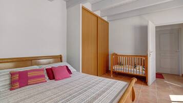Une chambre à coucher avec un lit, un berceau en bois, une armoire et une porte.
