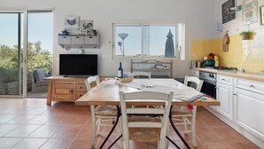 Een keuken met een eettafel, stoelen, een televisie en een raam.