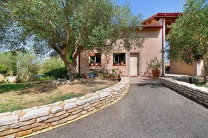A stone-walled driveway leading to a building with a red roof and multiple windows.