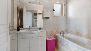 Een badkamer met een wastafel, spiegel, badkamermeubel en een bad.