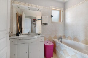 Un baño con lavamanos, espejo, tocador y bañera.