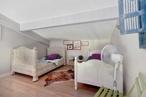 Un dormitorio con dos camas, un ventilador, una alfombra y decoración en la pared.