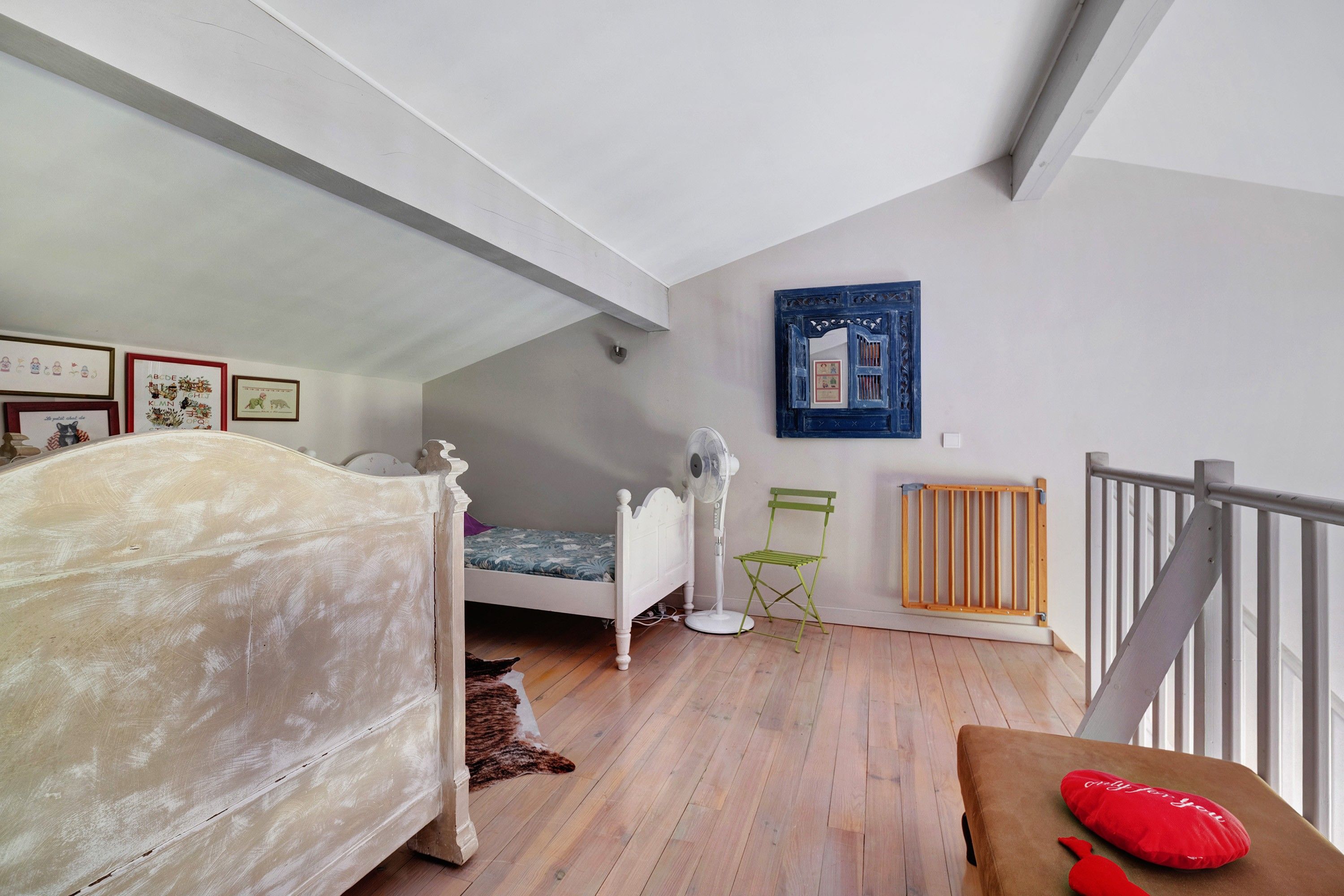 Un dormitorio con una cama, un ventilador de pie, un radiador y una silla plegable verde.