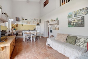 Amplia sala de estar con mesa y sillas de comedor, un sofá y una zona de cocina con estufa y alacenas.