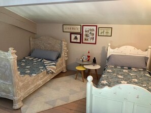 A bedroom with two beds, a small round table, and wall decorations.