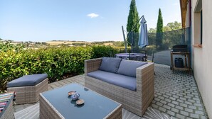 Een terras met rieten meubels, een tafel en uitzicht op het landschap.