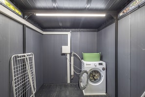 A compact laundry room with a washing machine and a drying rack. - Rural house 'Cal Duc' with private terrace, private garden, and Wi-Fi (el Mas Tomasí)