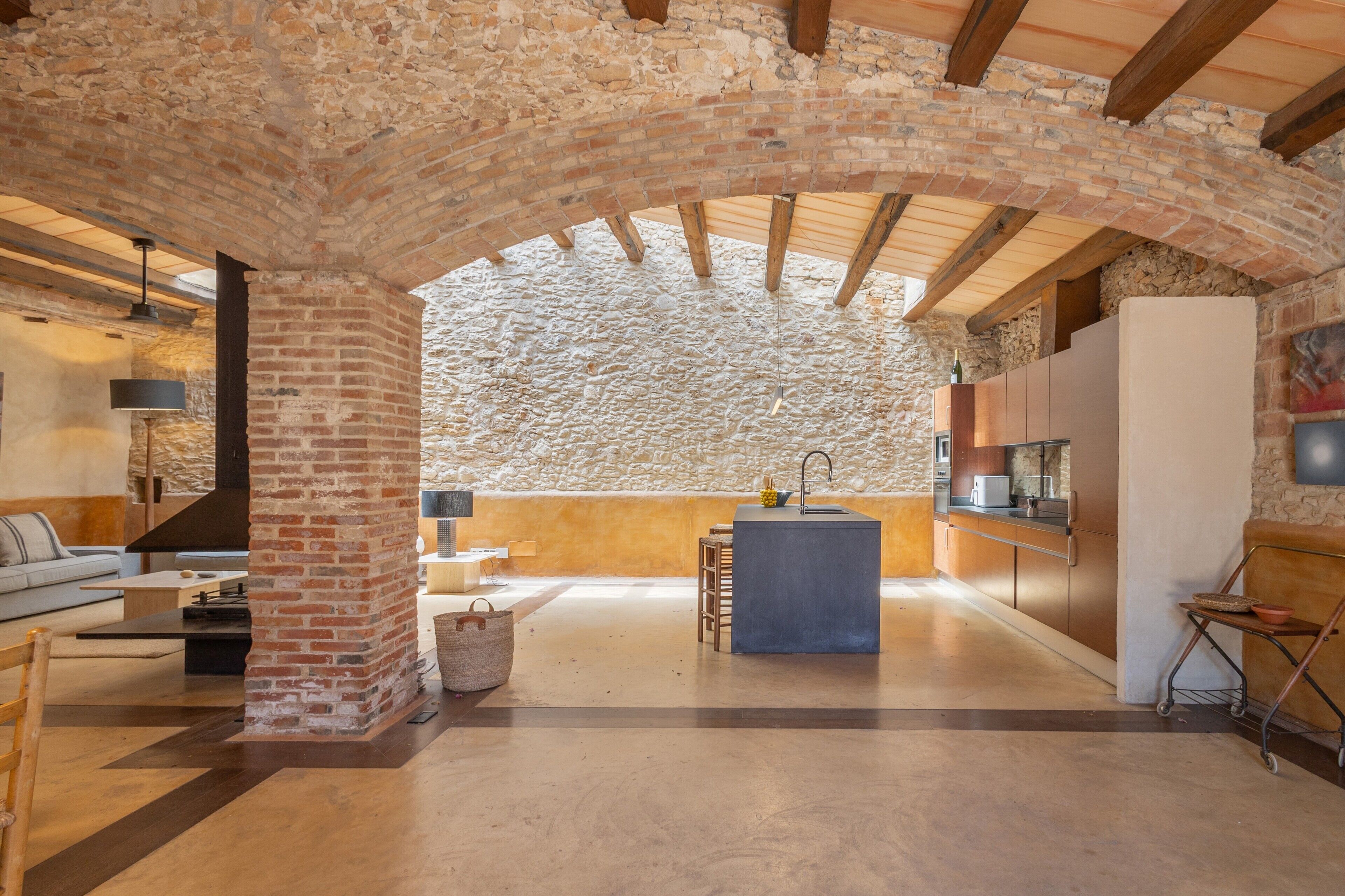 A spacious living area with a stone wall, a kitchen island, and a seating area.