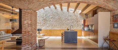 A spacious living area with a stone wall, a kitchen island, and a seating area.