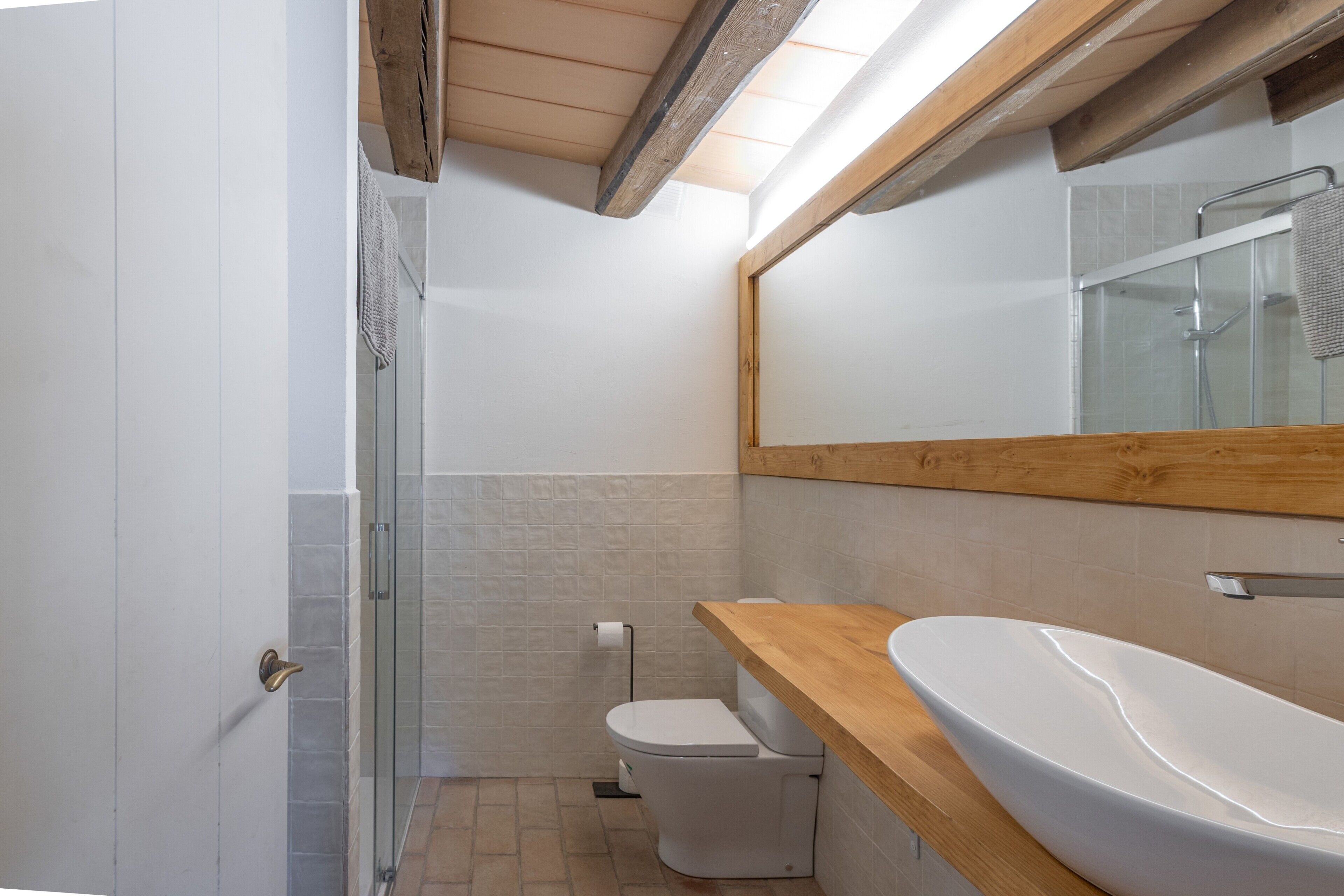 Une salle de bain moderne avec un meuble-lavabo en bois, une cabine de douche en verre et des toilettes.
