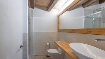 Une salle de bain moderne avec un meuble-lavabo en bois, une cabine de douche en verre et des toilettes.