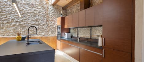 A modern kitchen with a stone wall, wooden cabinets, and a built-in oven.