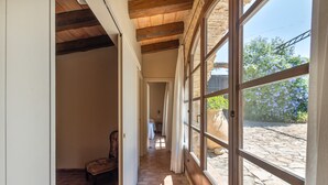 Un corridoio con soffitto in legno, una sedia e un letto in lontananza.