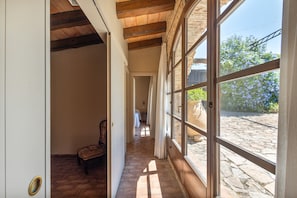 A corridor with a wooden ceiling, a chair, and a bed in the distance. - Rural house 'Cal Duc' with private terrace, private garden, and Wi-Fi (el Mas Tomasí)