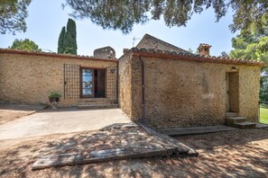 A stone building with a tiled roof, a wooden door, and a small porch area.