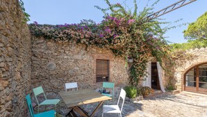 Un patio esterno con un muro in pietra, un tavolo di legno e sedie.