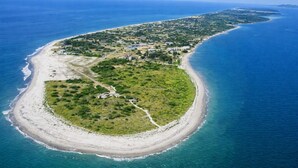 Luchtbeeld van een kustbezit met een strand, een weg naar het strand en een groep gebouwen.