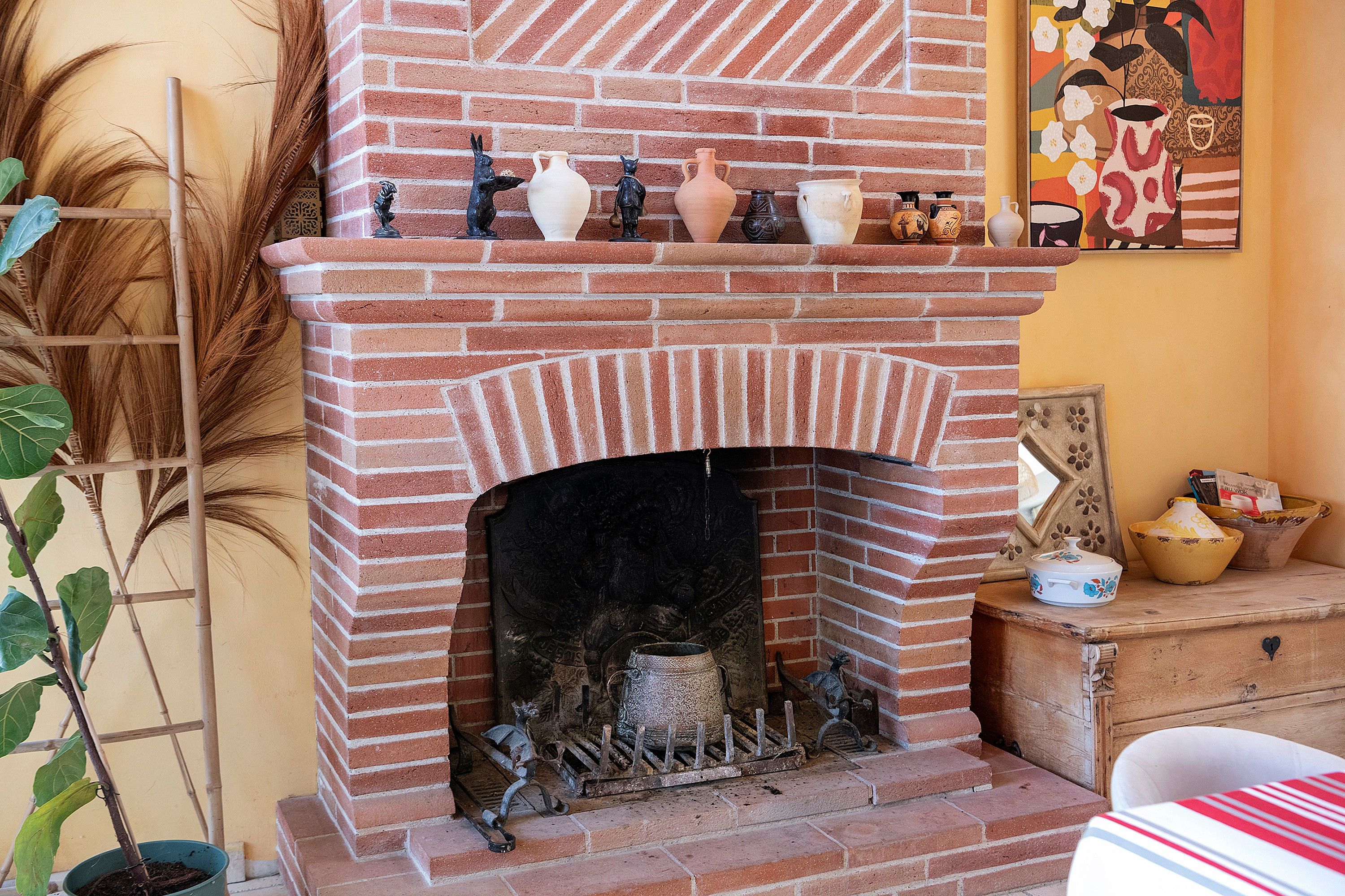 Una chimenea de ladrillo con un repisa que exhibe diversos objetos de cerámica.