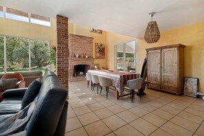 A spacious living area with a fireplace, dining table, and a large wardrobe.