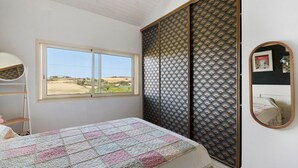 Un dormitorio con cama, ventana, armario y espejo.