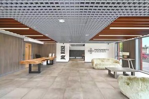 A modern reception area with a high ceiling, wooden beams, and a central wall with the logo 'IQ RISE' and 'PROSPERITY & DEVELOPMENTS'. - Apartment Sleeps 4 - Air Con, City Centre, Wifi (Birmingham)