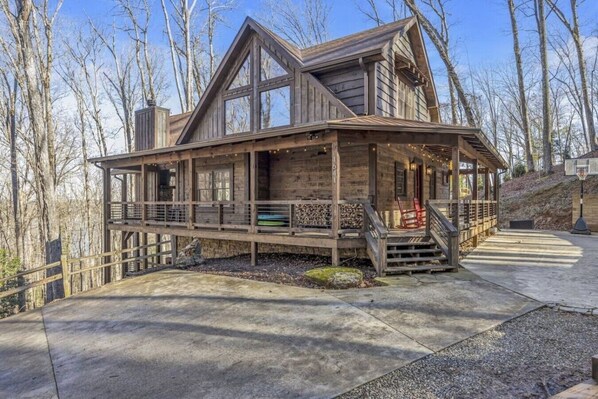 A wooden cabin with a porch, a basketball hoop, and a stone foundation. - Blue Ridge Escape | Luxury Mtn. Cabin near Lake BR (Blue Ridge)